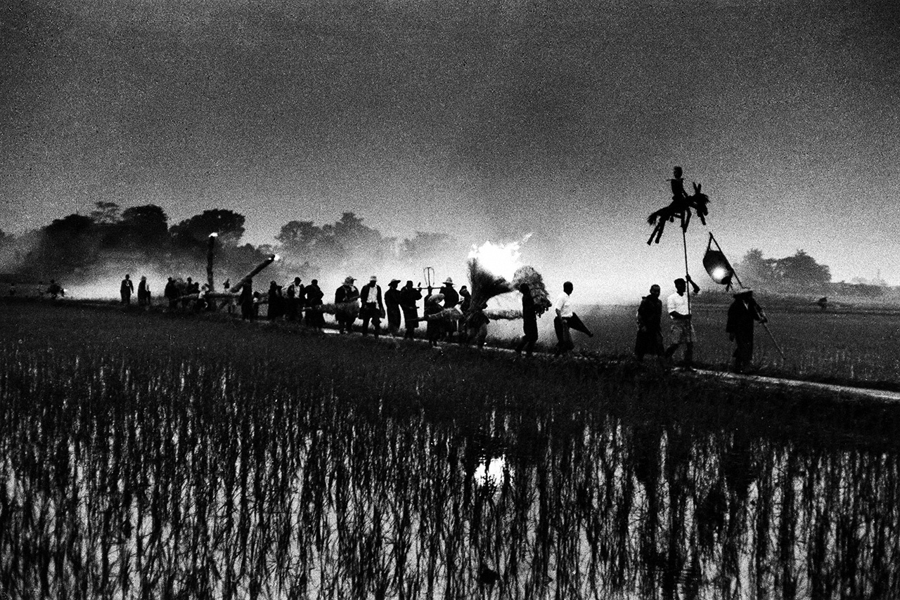 “Expulsión de Plagas”. La procesión Mushi-okuri se realiza en Sobue, ciudad de Inazawa, prefectura de Aichi. Al atardecer, la imagen de la gente caminando por los senderos de los arrozales, guiada por un guerrero de paja conocido como Tairano Sanemori, resulta verdaderamente etérea. (Fotografía de 1957)