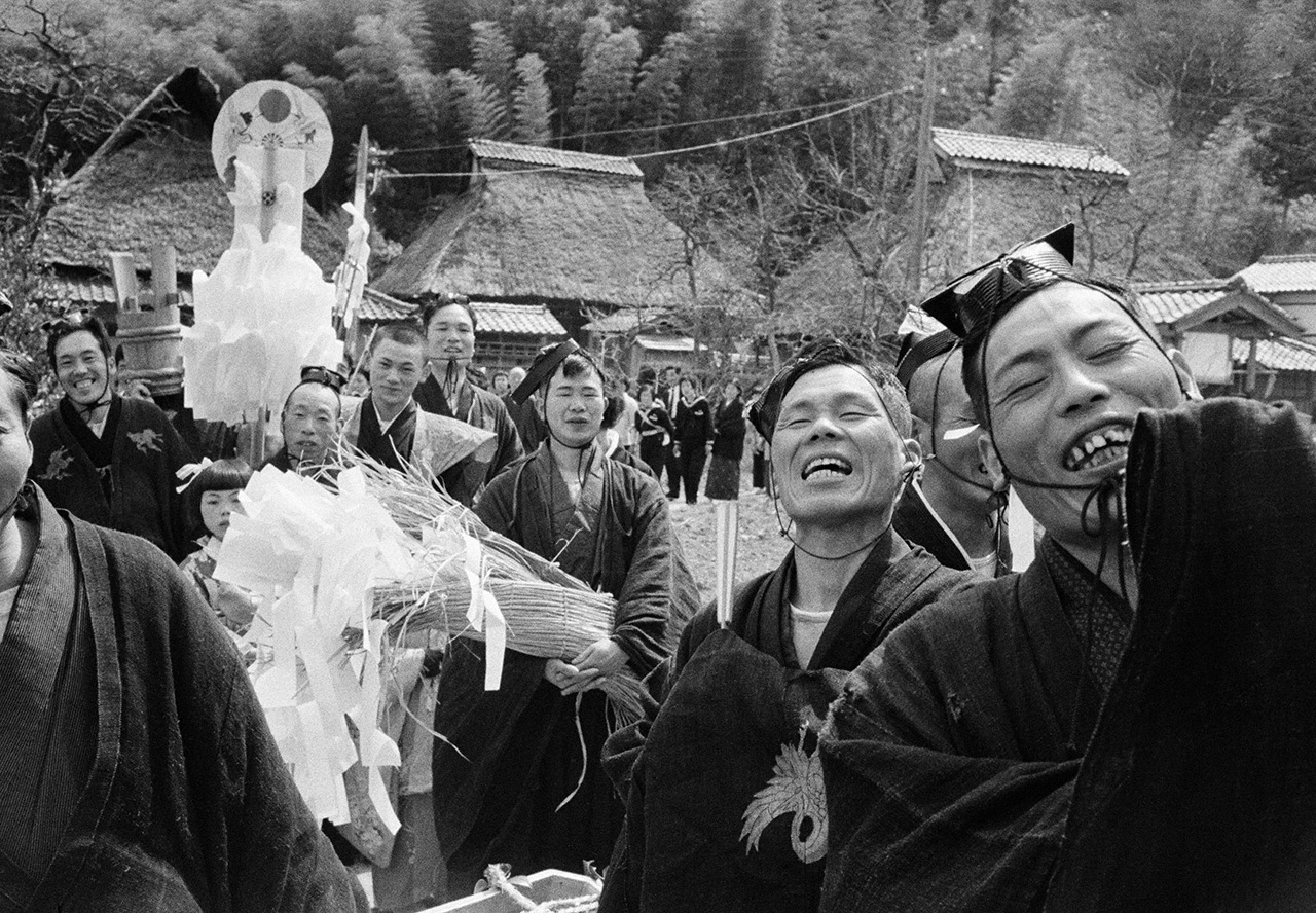 “Procesión del pueblo”. Una escena de los ritos sagrados en el santuario Kunitsu, en la localidad de Mikata, prefectura de Fukui. Tras concluir el banquete festivo en la tōya (la casa del jefe del festival), la procesión se pone en marcha hacia el santuario, llevando consigo serpentinas de papel sagradas. No falta el sake, por lo que todos parecen estar de muy buen humor. (Fotografía de 1973)