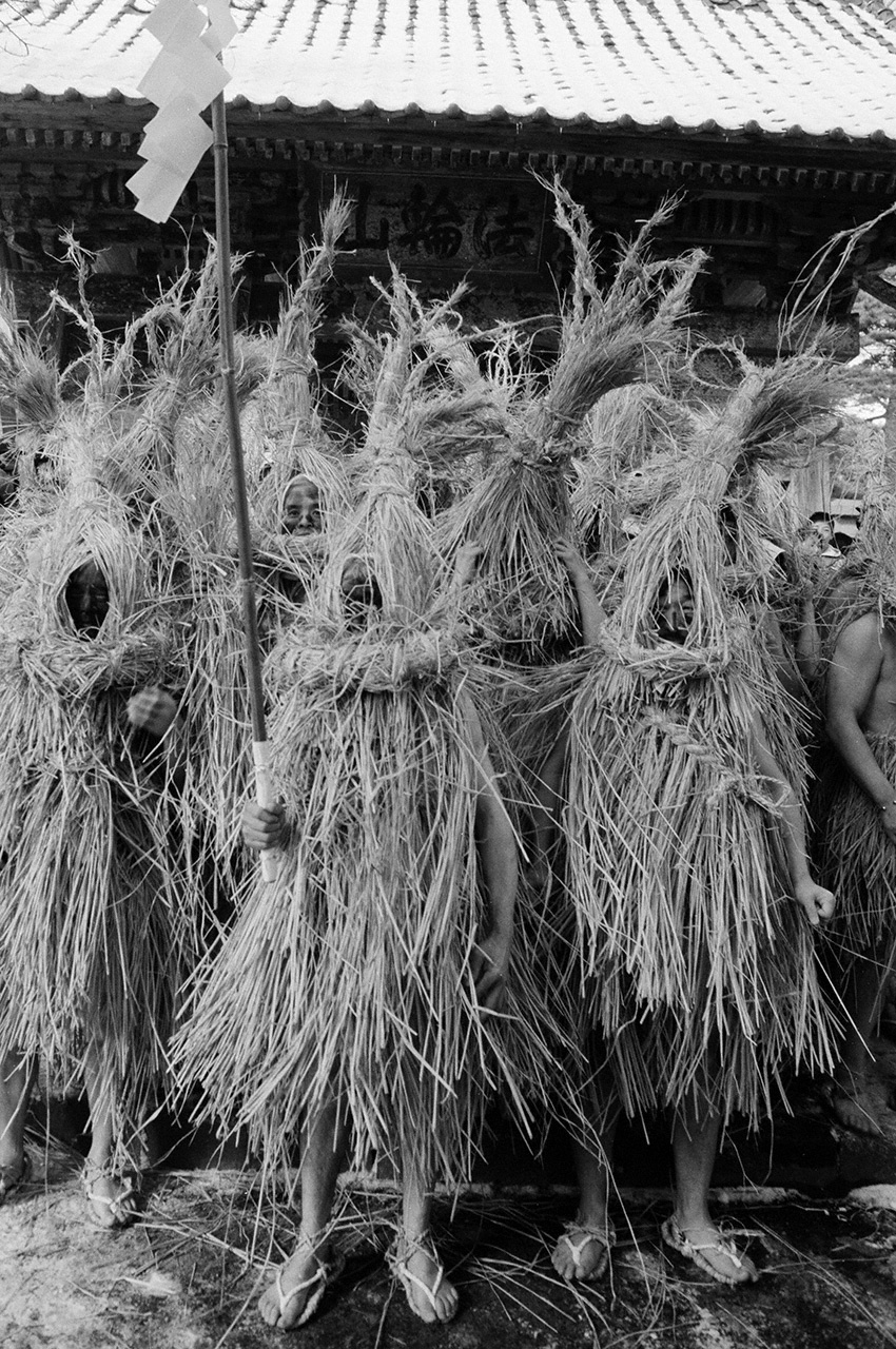 “Mensajeros de la prevención de incendios”. Los hombres que han alcanzado una edad desafortunada se visten con un traje hecho completamente de paja. El primer día del año del caballo salen a las calles con serpentinas de papel sagradas, profiriendo extraños gritos y rociándose con agua para prevenir incendios. Se puede ver cómo encarnan plenamente su papel de mensajeros divinos. (Fotografía realizada en la ciudad de Towa, prefectura de Miyagi, 1996)