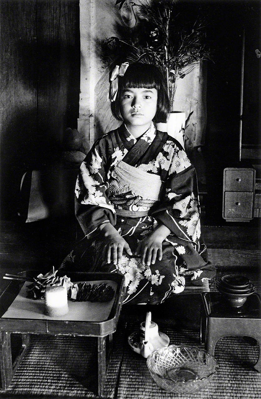 “Decimotercer cumpleaños”. Celebración del decimotercer cumpleaños según el sistema tradicional japonés de cálculo de edad. Para las niñas, es la primera y última ceremonia que se celebra en la casa de sus padres, por lo que se celebra por todo lo alto con el uso de un kimono ceremonial recién confeccionado. La expresión de la niña, que transmite un nerviosismo palpable, es particularmente llamativa. (Fotografiado en la isla de Okinoerabu, 1957)