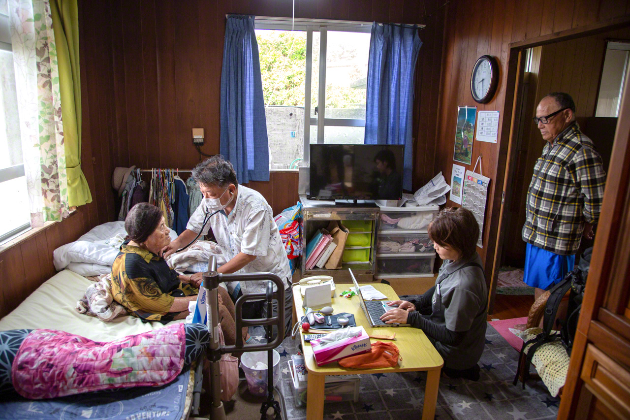 Yasukawa atendiendo a Isa Tsuru, una habitante de Ōgami de 95 años. Yasukawa la visita una o dos veces al mes. A la derecha, Isa Teruo, hijo de Tsuru, contempla la escena.