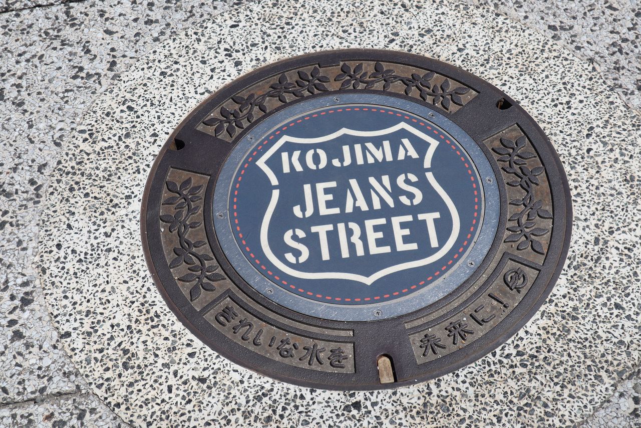Una alcantarilla de la Jeans Street, en Kojima. Se puede apreciar el detalle del logo y los puntos de cosido de color naranja. (Fotografía de la Cámara de Comercio e Industria de Kojima)
